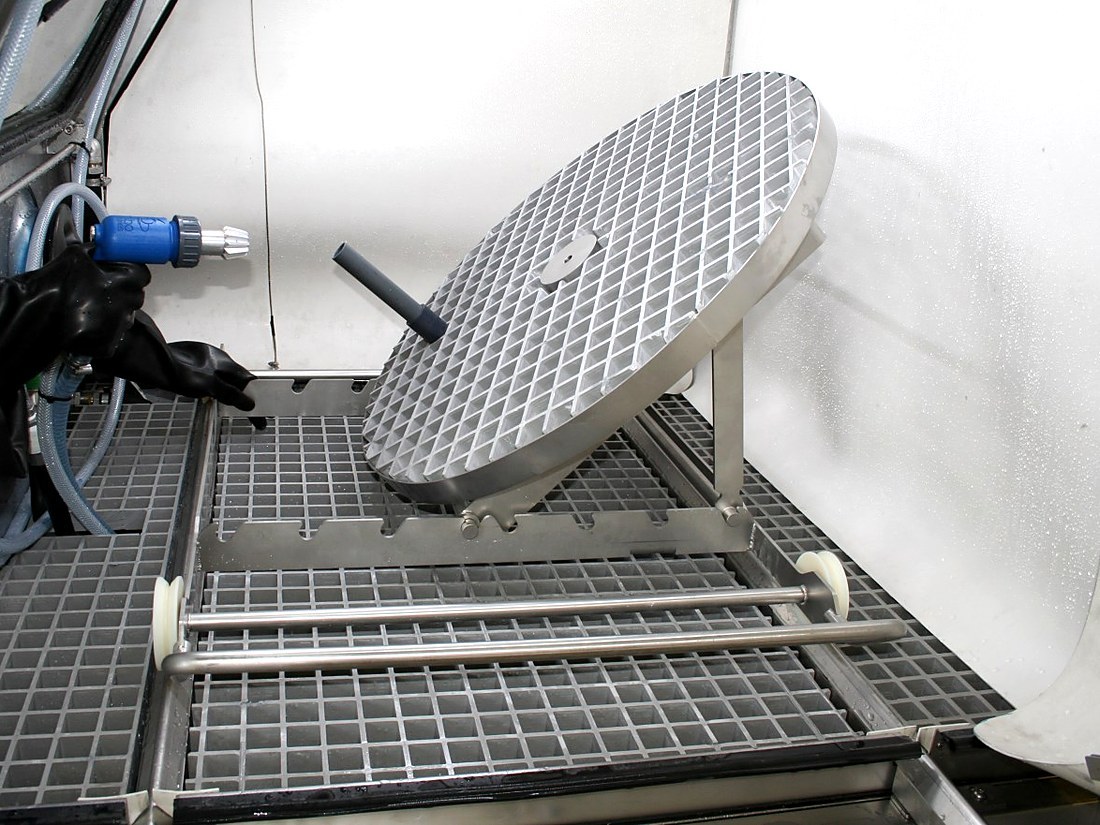 Tilting turntable inside the wet blasting cabinet, with the process gun in the operator's hand
