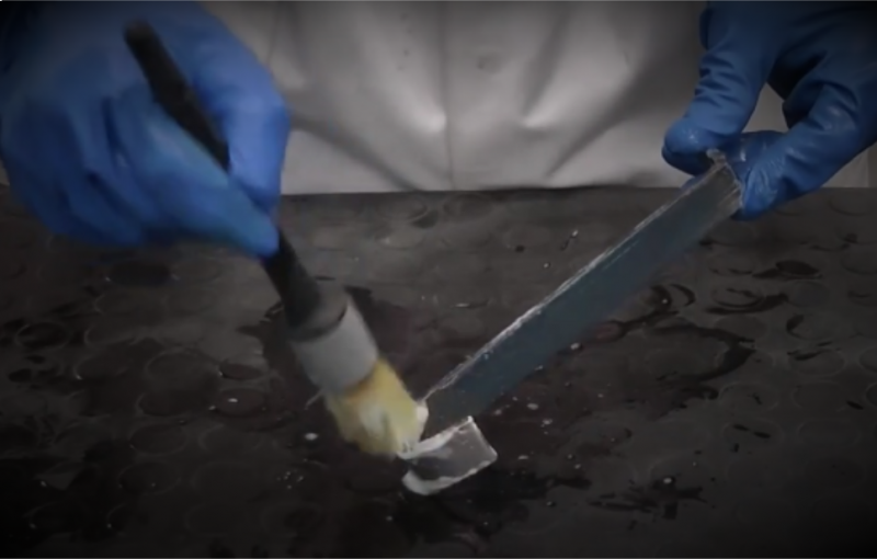 Applying blacking paste with a brush to a steel surface