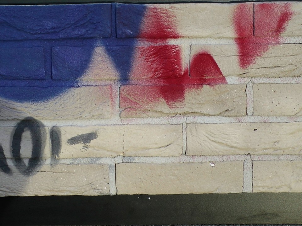Grafiti eliminado en parte de un ladrillo cara vista amarillo, con el ladrillo y las juntas sin daños