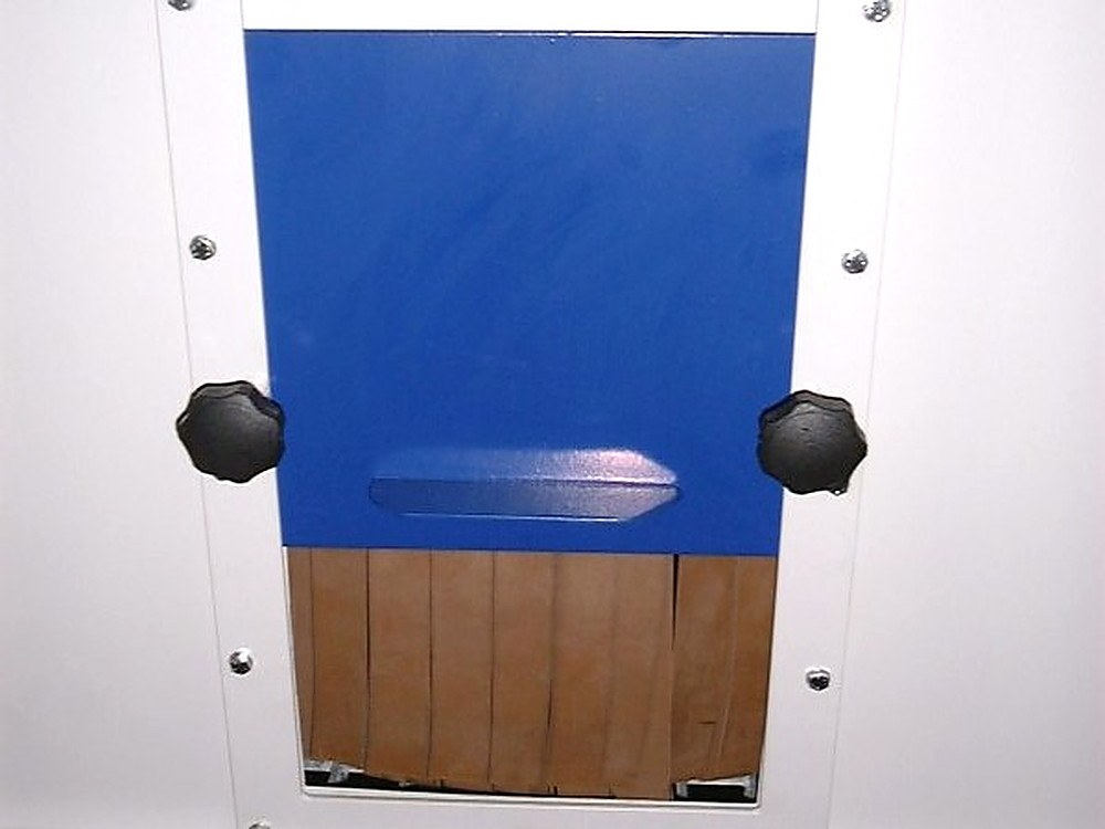 Closable pass-through opening in the side wall of a blast cabinet, with rubber flaps behind it