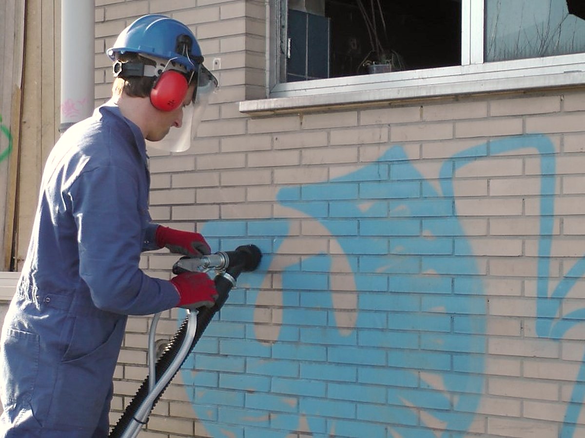 Straler die graffiti van een bakstenen gevel verwijdert