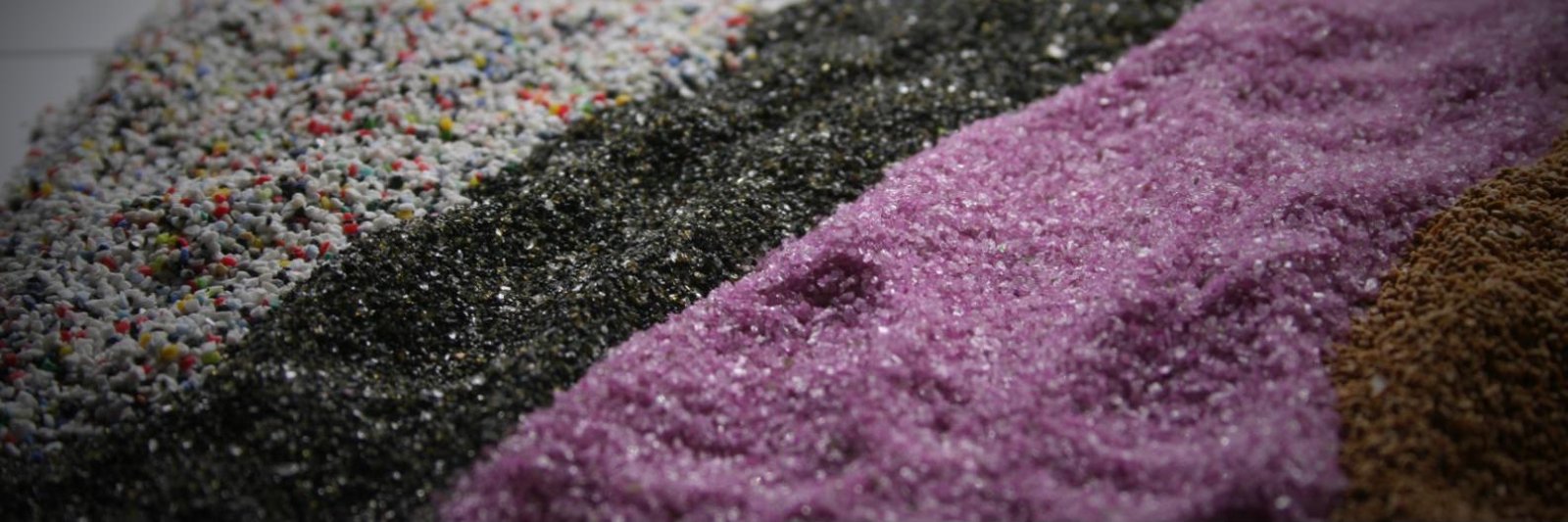 Vier straalmiddelen in verschillende kleuren en korrelgroottes naast elkaar