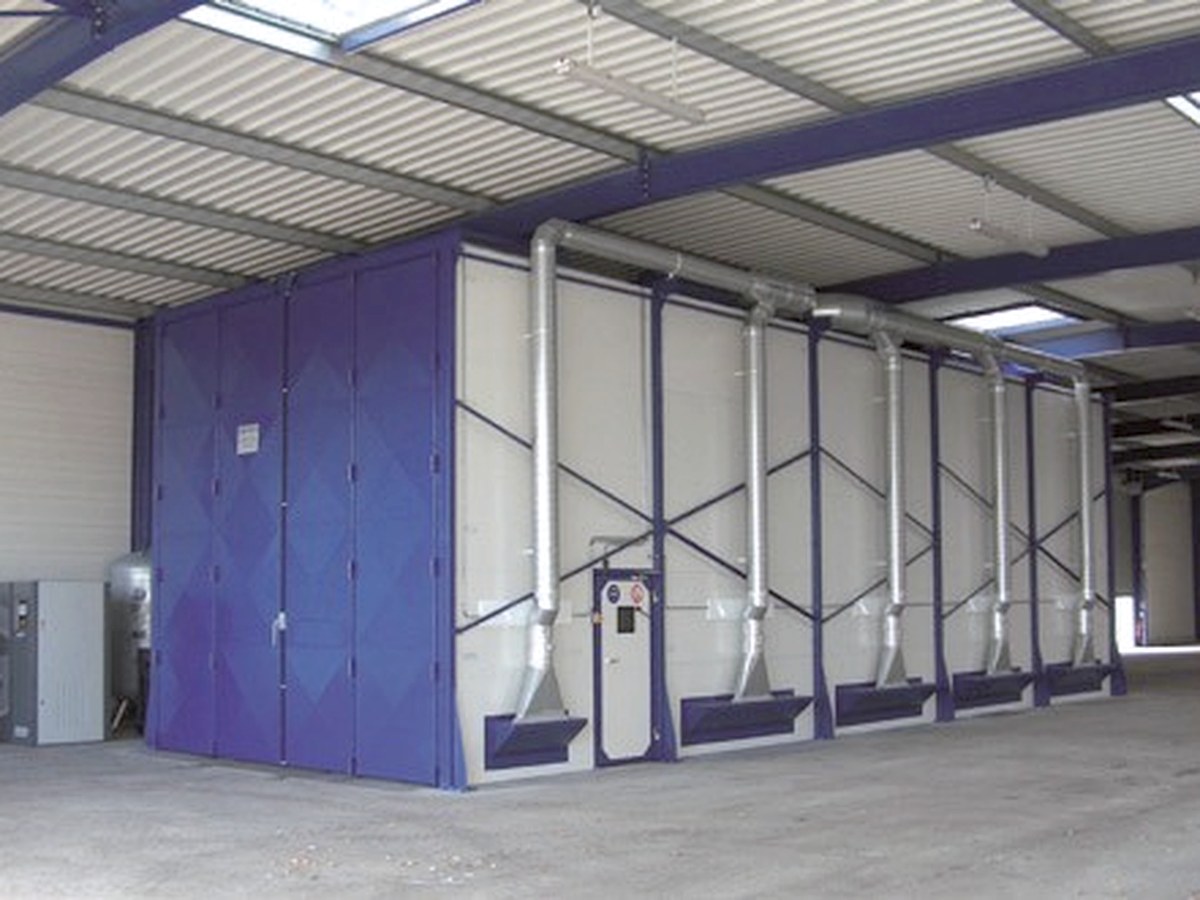 Industriële straalhal met blauwe labyrintdeuren en afzuiging, in een werkhal